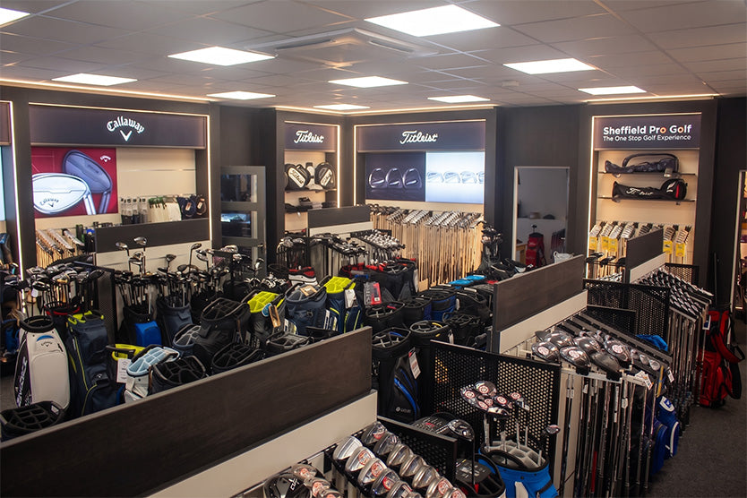 Golf store interior with various golf equipment and brand displays.